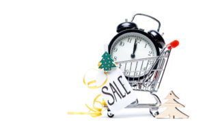 Picture of trolley with gold alarm clock, Christmas tree, greeting card, ribbon on blank white background. Place for text