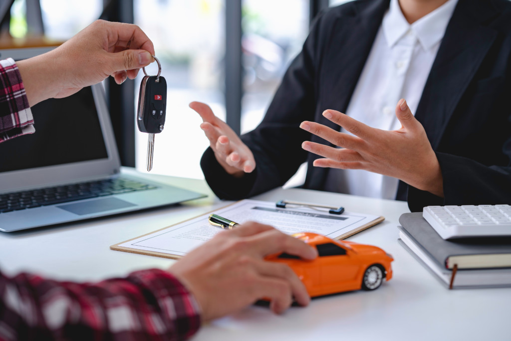 Insurance officers hand over the car keys after the tenant. have signed an auto insurance document or a lease or agreement document Buying or selling a new or used car with a car