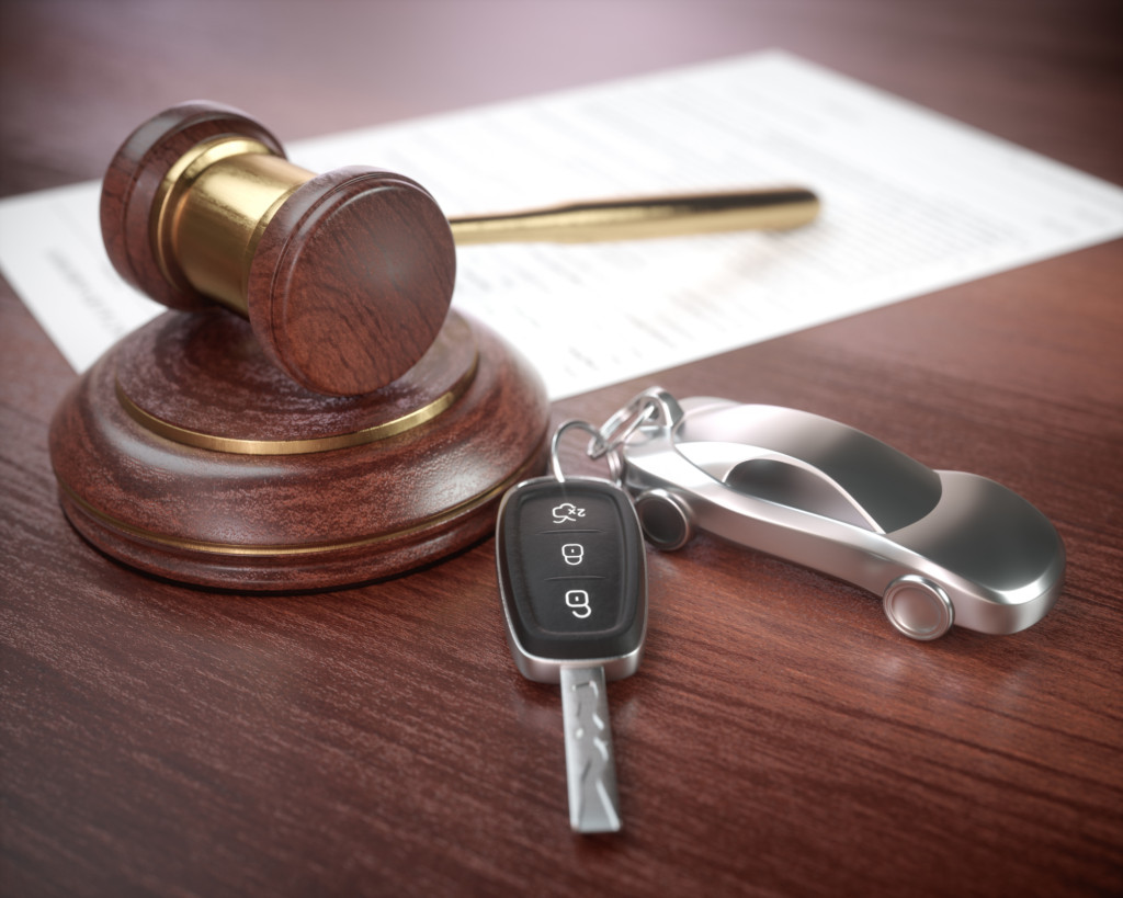 Auction hammer with golden details, a car key next to it and a contract in the background.